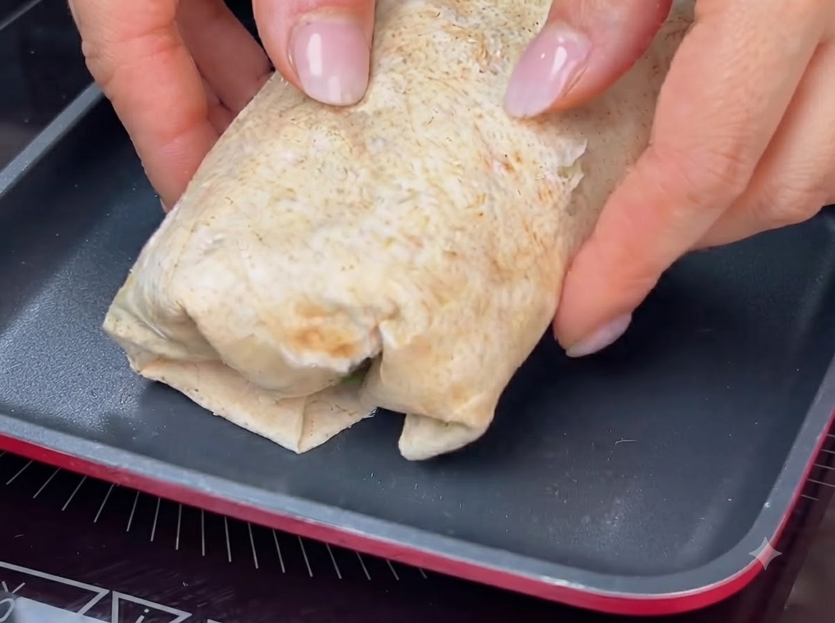 Ein gerollter Wrap wird in einer heißen Pfanne getoastet, um eine goldbraune Kruste zu erhalten.