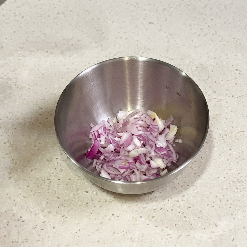 Fein gehackte rote Schalotten und Frühlingszwiebeln in einer kleinen Metallsale, bereit zum Mischen mit Gewürzen.