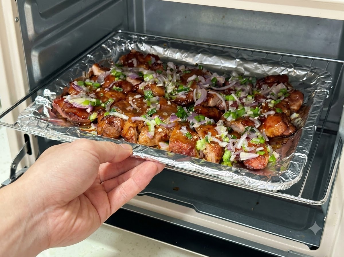Ein mit saucebedeckten Schweinefleischscheiben gefülltes Backblech wird wieder in eine Heißluftfritteuse geschoben.