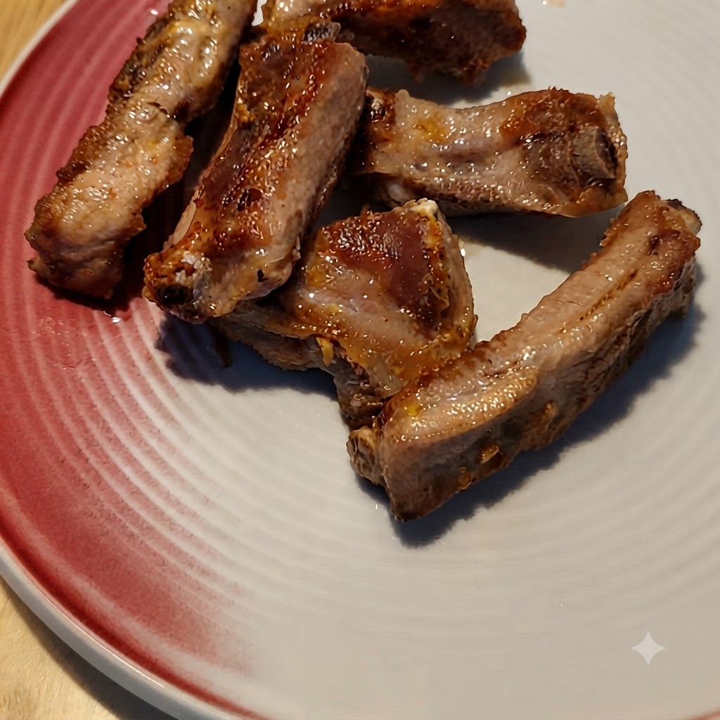 Kaffeesoße wird über angebratene Schweinerippchen in einer Pfanne gegossen.