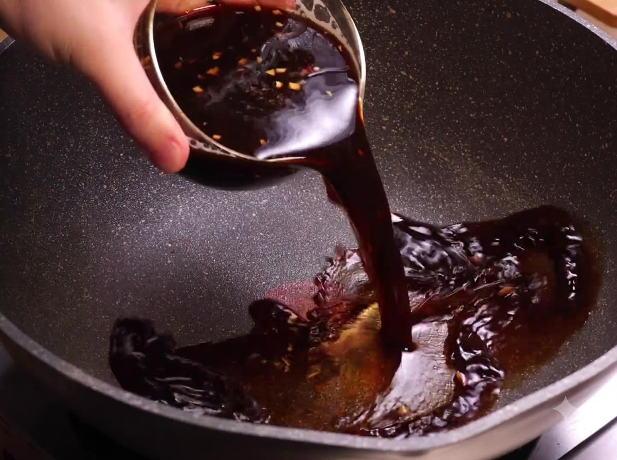 Eine Schüssel mit dunkler Kaffeesauce wird in einen erhitzten Wok gegossen.