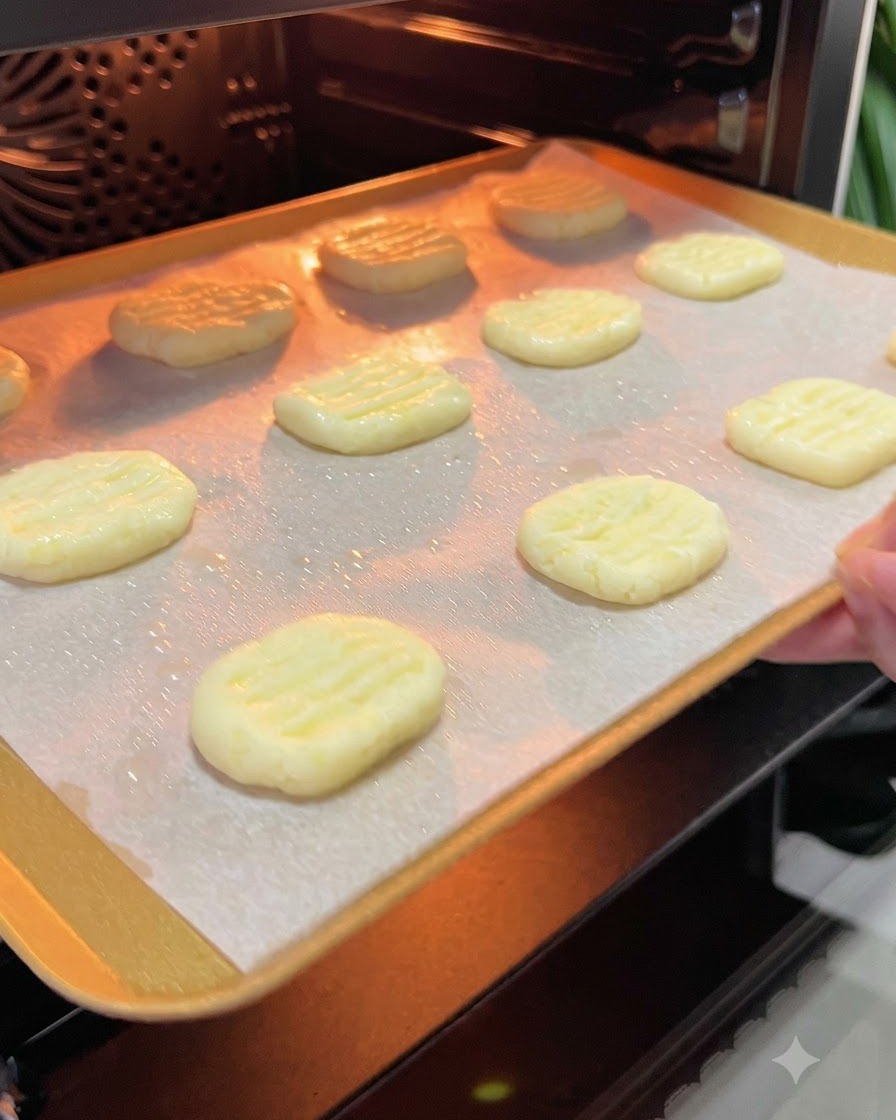 Ein Backblech mit Kartoffelpuffern wird in den glühenden Innenraum eines vorgeheizten Ofens geschoben.