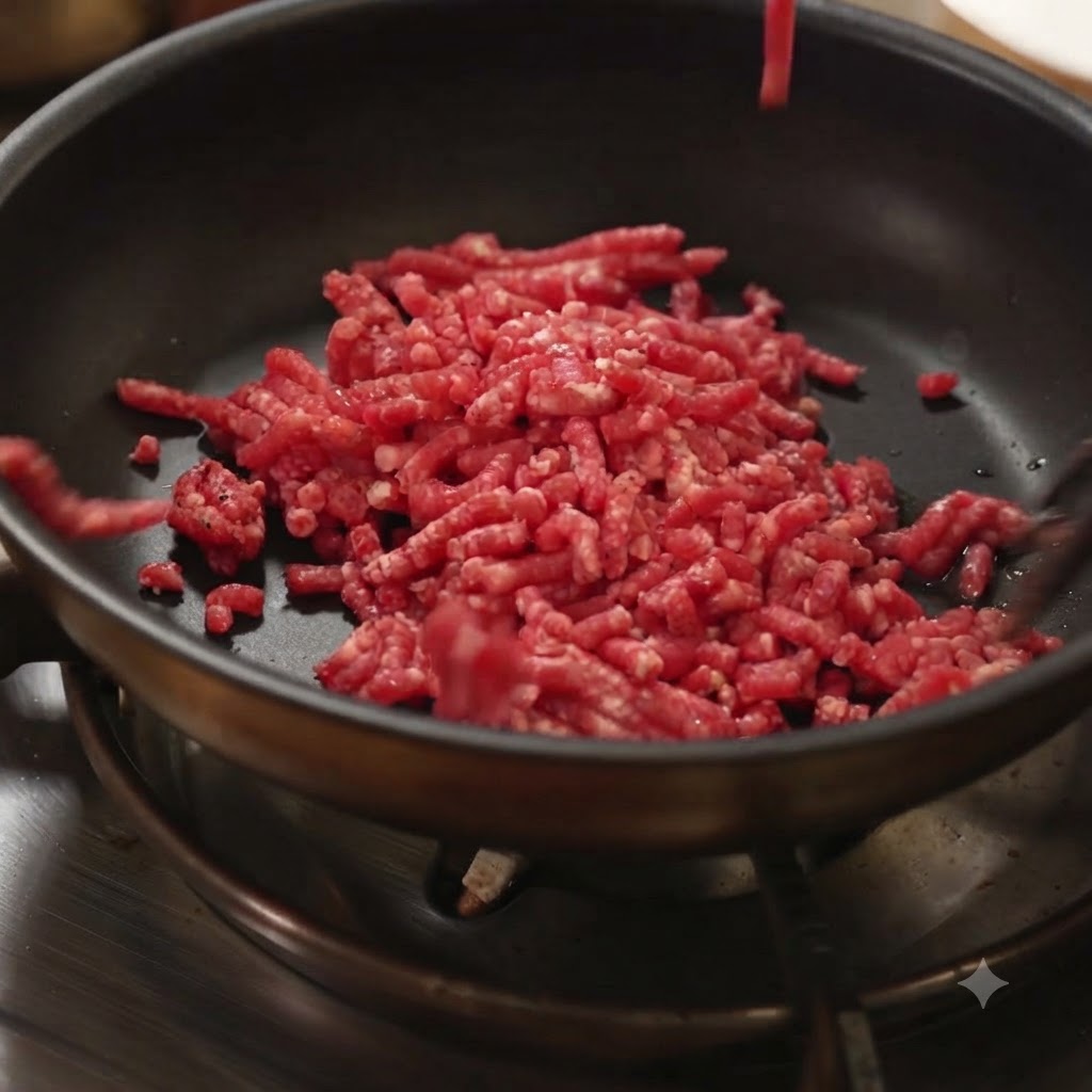 Rohes Hackfleisch wird in eine heiße schwarze Bratpfanne auf einem Herd gegeben.