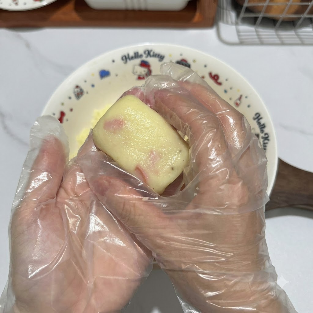 Mit Handschuhen bekleidete Hände formen ein Stück Kartoffelteig zu einem ordentlichen rechteckigen Taler.