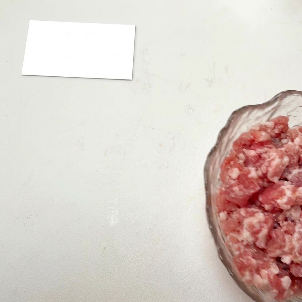Hackfleisch in einer Glasschüssel mit zugefügten Gewürzen.