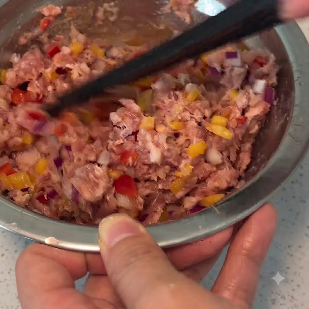 Ein Paar Essstäbchen vermischt Hackfleisch, Gemüse und Gewürze in einer Metallschüssel.