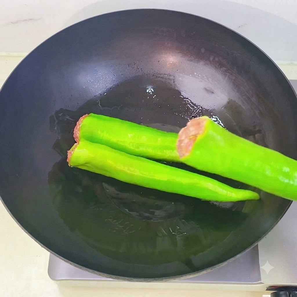Gefüllte grüne Paprika werden nacheinander in einen erhitzten Wok mit Öl gelegt.