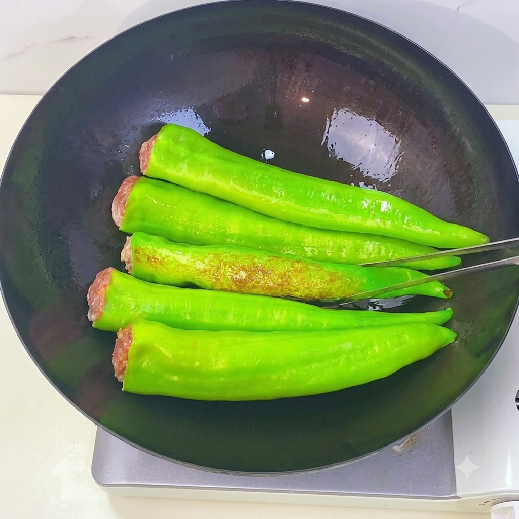 Grüne Paprika braten im Wok und zeigen braune Tigerfellflecken, während sie mit einer Küchenzange gewendet werden.