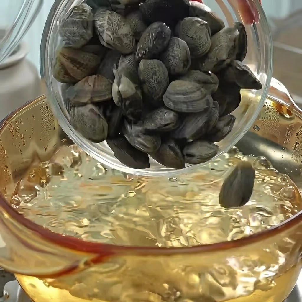 Muscheln werden zum Kochen und zur Brüheherstellung in einen Topf mit kochendem Wasser gegeben.