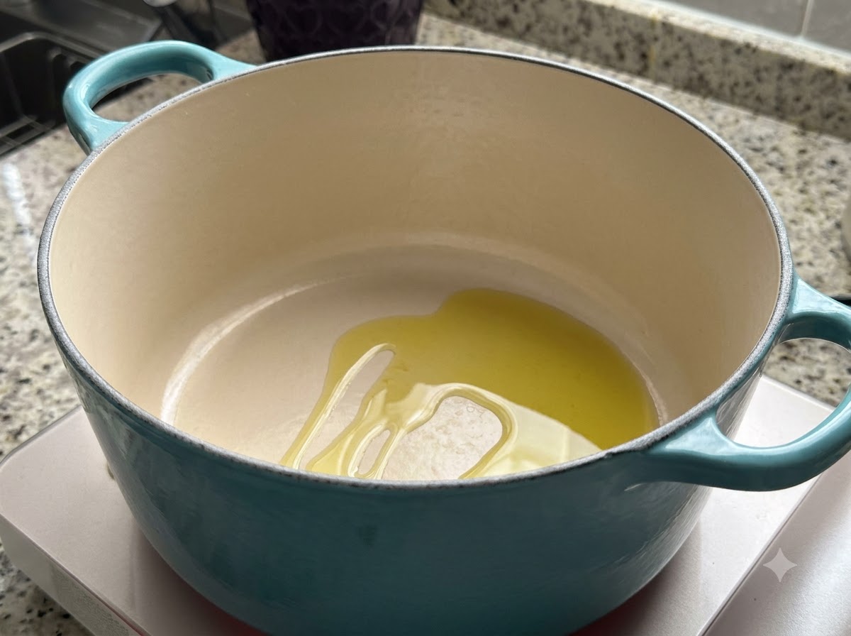 Ein türkisfarbener Dutch Oven auf dem Herd mit einer Menge Olivenöl darin.
