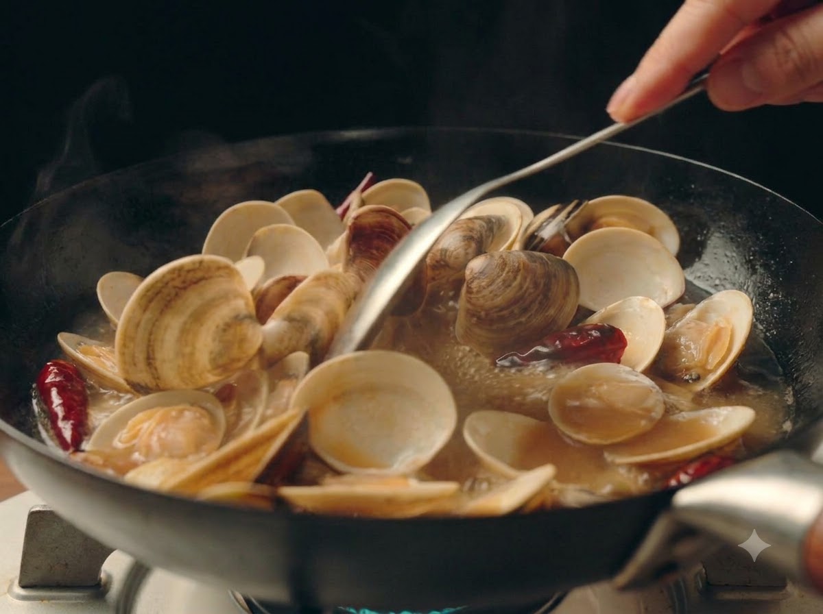 Fein gehackte Frühlingszwiebeln werden über die blubbernden Muscheln in der Pfanne gestreut.