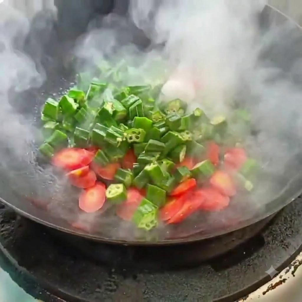 In Scheiben geschnittene Okra und Karotten werden in einem heißen Wok mit aufsteigendem Dampf angebraten.