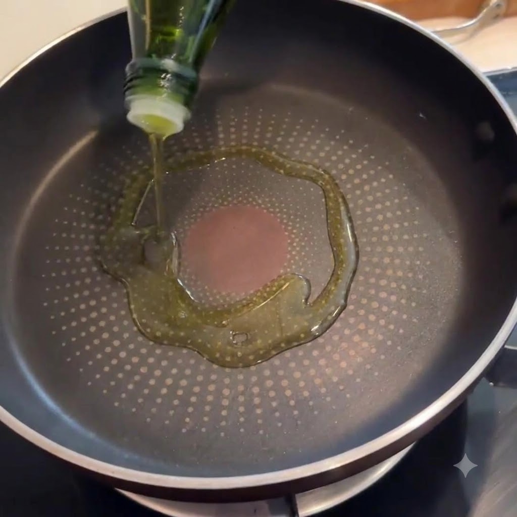 Speck brutzelt in einer Pfanne, deren Boden mit Olivenöl benetzt ist.