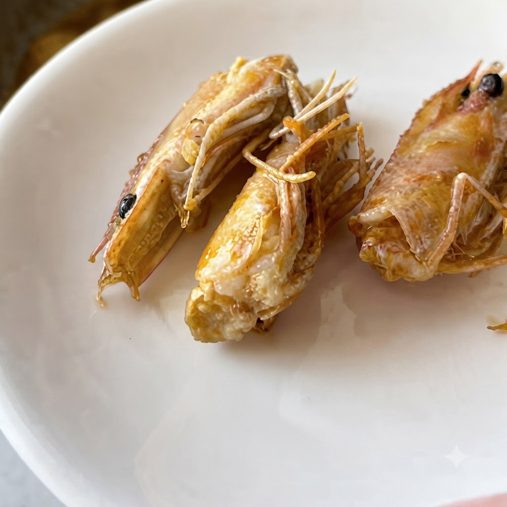 Fein gehackter Knoblauch und rote Chilischoten braten in schimmerndem Öl in einer Edelstahlpfanne.