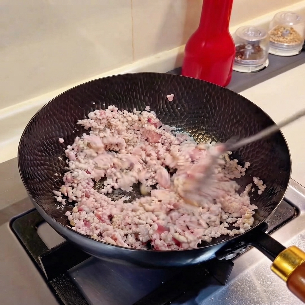 Gehackte Frühlingszwiebeln und gehackter Knoblauch werden mit Hackfleisch im Wok vermengt.