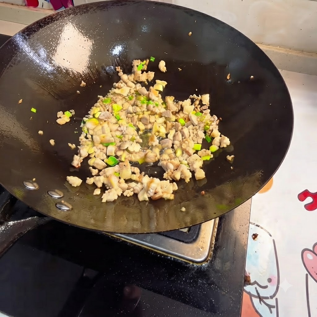 Hackfleisch und Aromaten werden in einem Wok pfannengerührt.