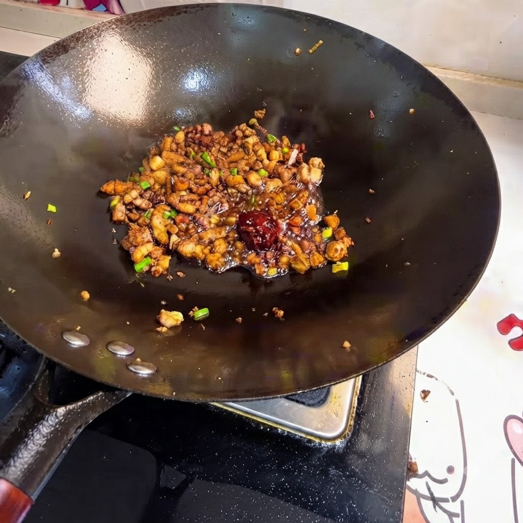 Ein Klecks Bohnenpaste zwischen dem gebratenen Fleisch im Wok.