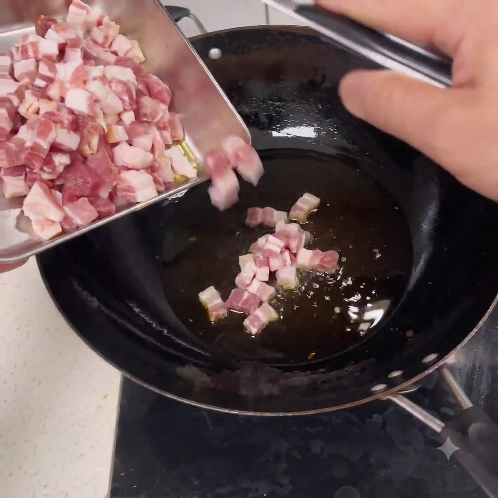 Rohe gewürfelte Schweinefleischstücke rutschen von einem Metalletablett in einen Wok mit heißem Öl.