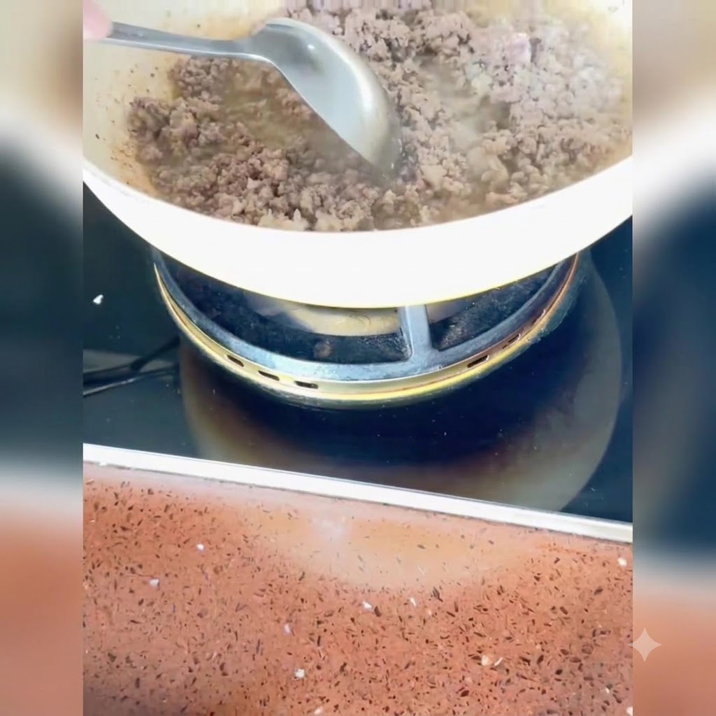 Gehackte Frühlingszwiebeln, Ingwer und Knoblauch werden in der Pfanne unter das gekochte Fleisch gerührt.