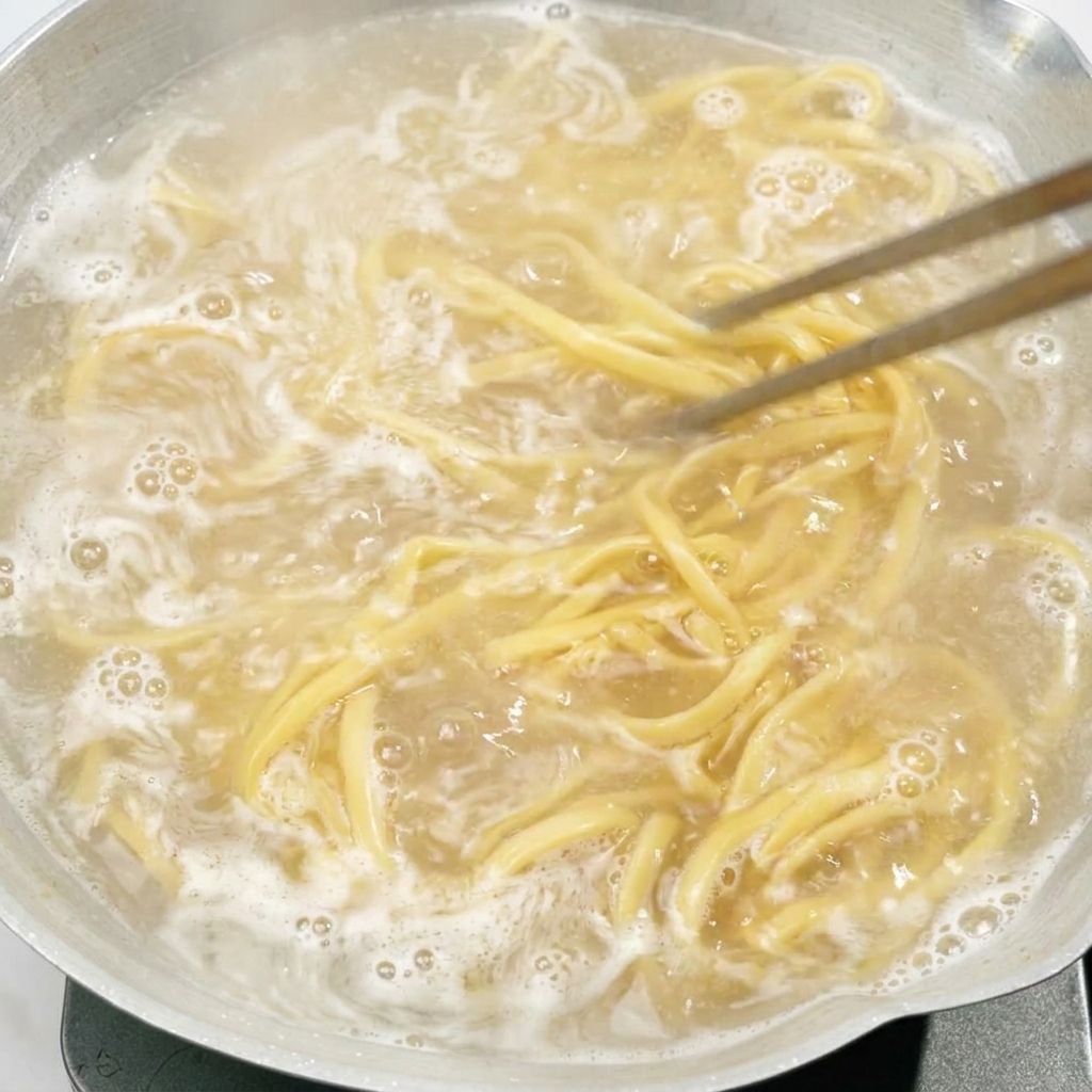 Stäbchen rühren Nudeln um, die in einem Topf mit Wasser kochen.