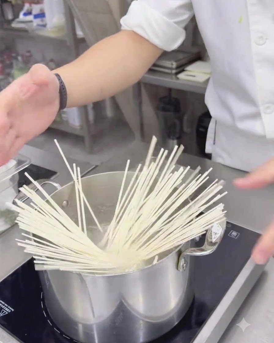 Getrocknete weiße Udon-Nudeln werden in einen Edelstahltopf mit kochendem Wasser gegeben.