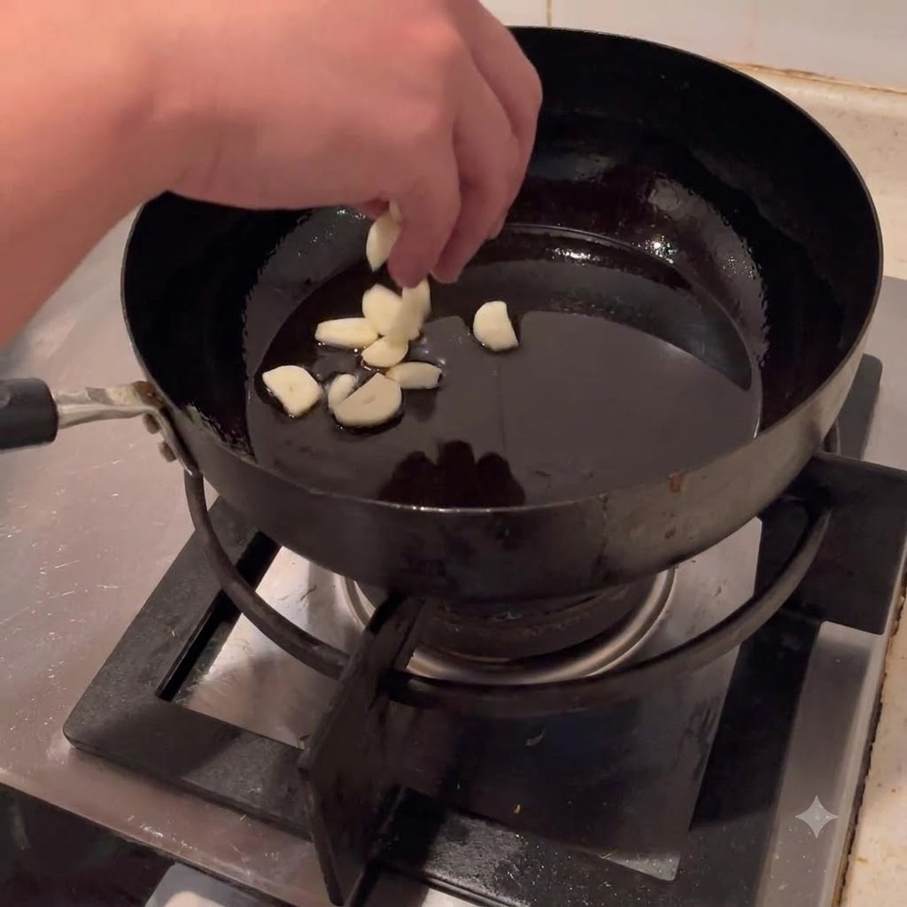 Knoblauchscheiben werden in heißes Öl in einem Wok gegeben.