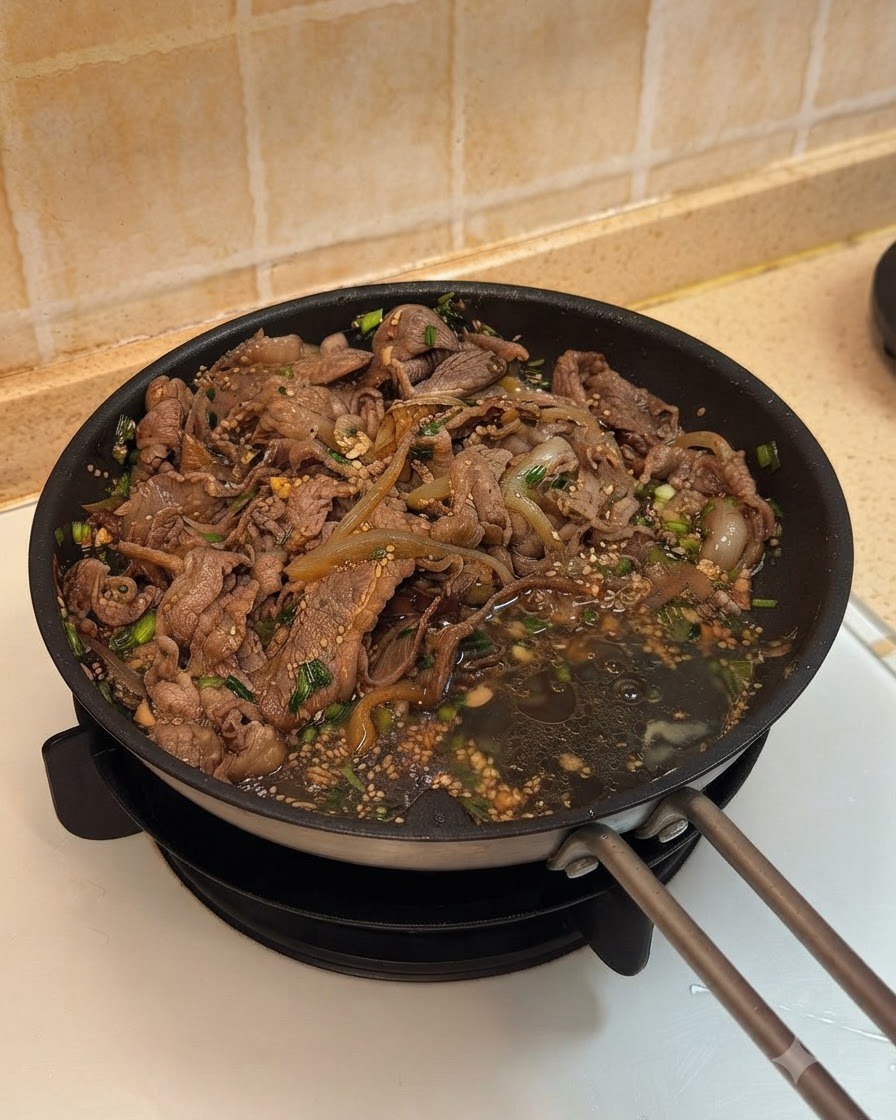 Zwei Eier werden neben dem gekochten Rindfleisch und den Zwiebeln in die Pfanne geschlagen.