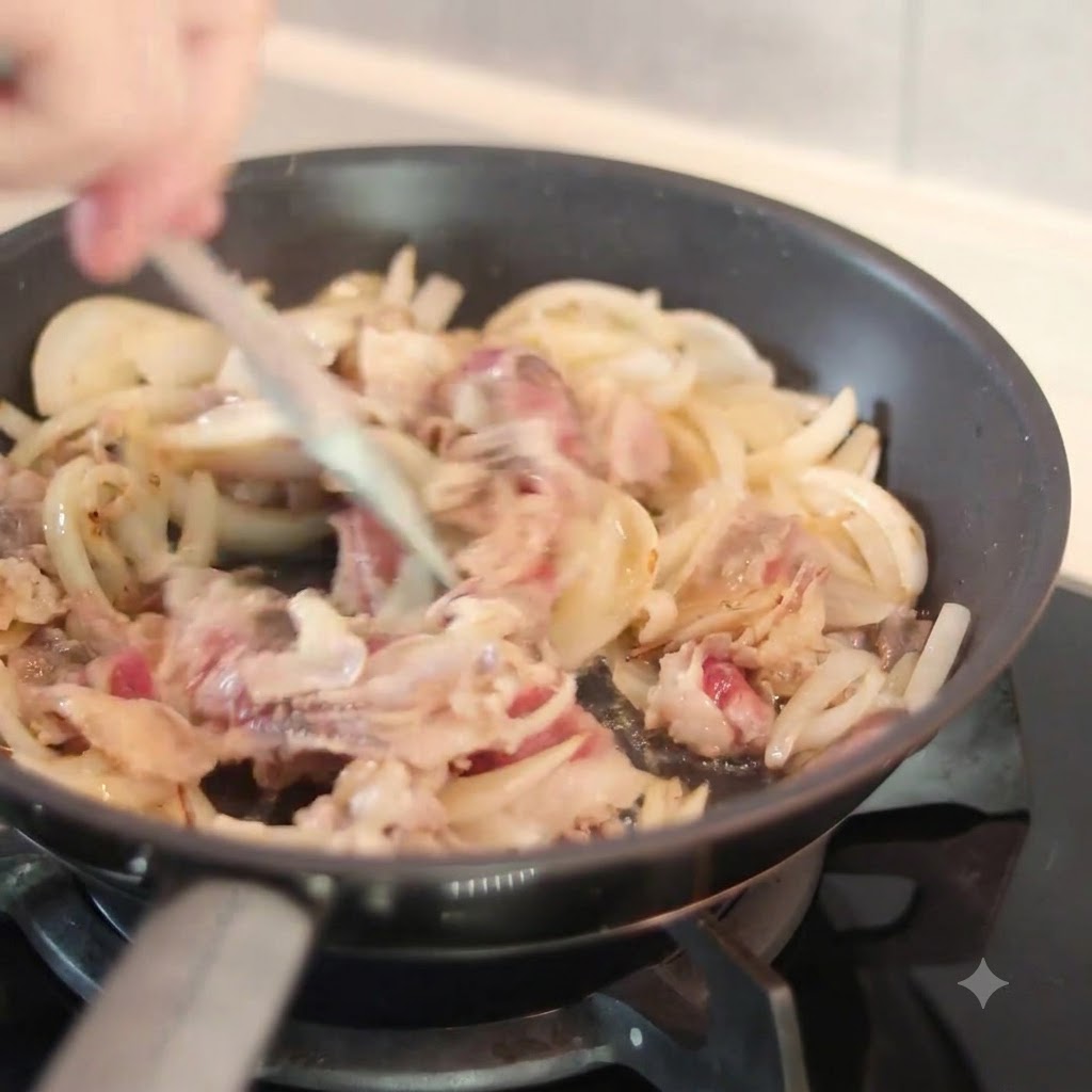 Eine dunkle Sauce wird von oben in eine heiße Bratpfanne mit geschnittenen Zwiebeln und Rindfleischstücken gegossen, während mit einem Spatel umgerührt wird.