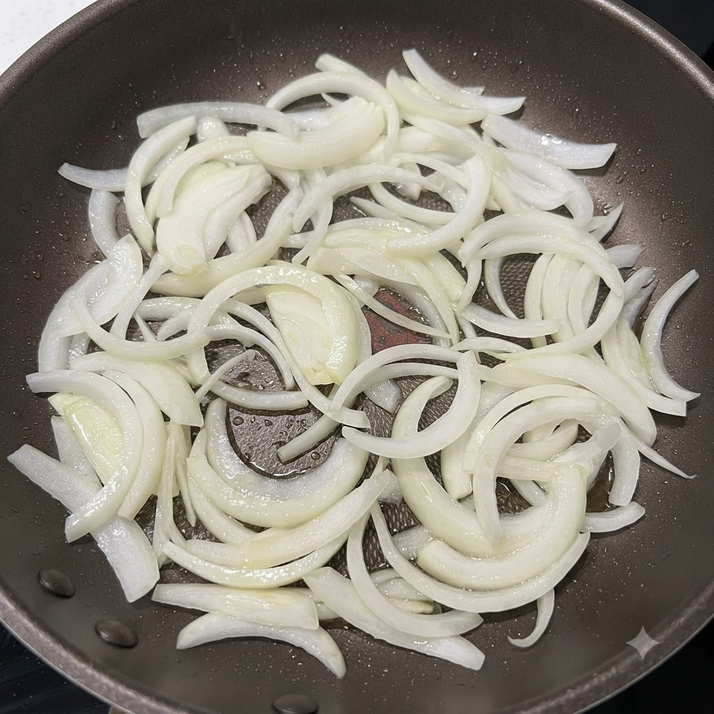 Zwiebelstreifen werden in einer heißen Pfanne angebraten, bis die Ränder leicht gebräunt sind.