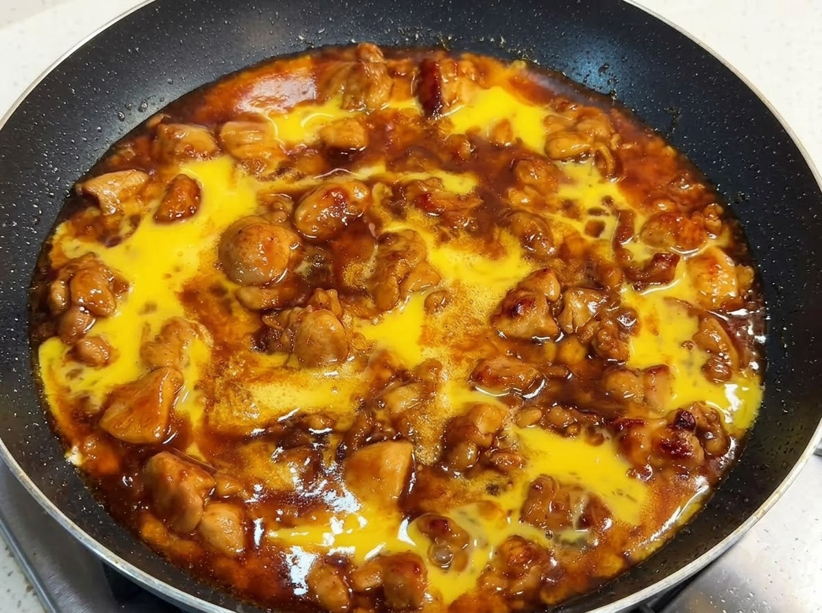 Eine Pfanne mit Hähnchenstücken und reichhaltiger Sauce, übergossen mit roher Eimasse und mit einem Deckel verschlossen.