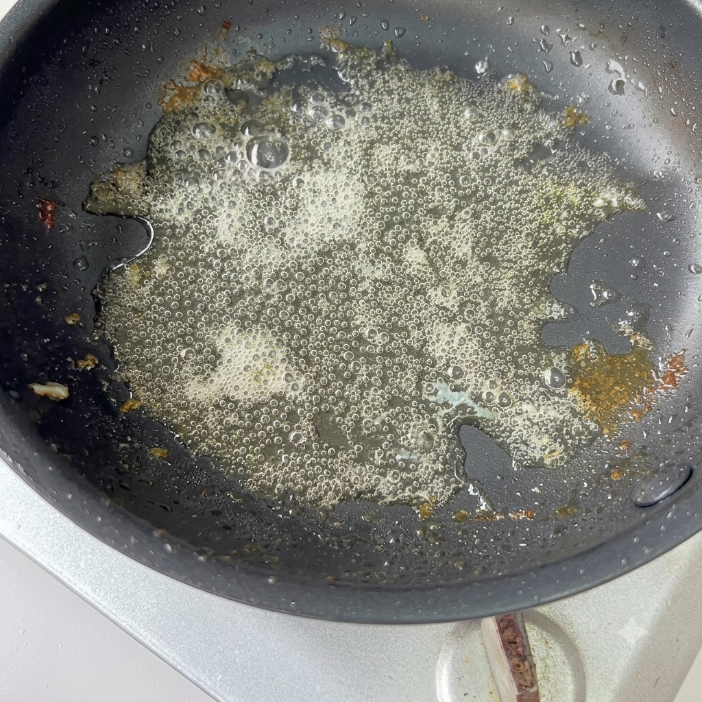 In Scheiben geschnittene rote Zwiebeln werden in einer heißen Pfanne mit übrig gebliebenem Öl sautiert.