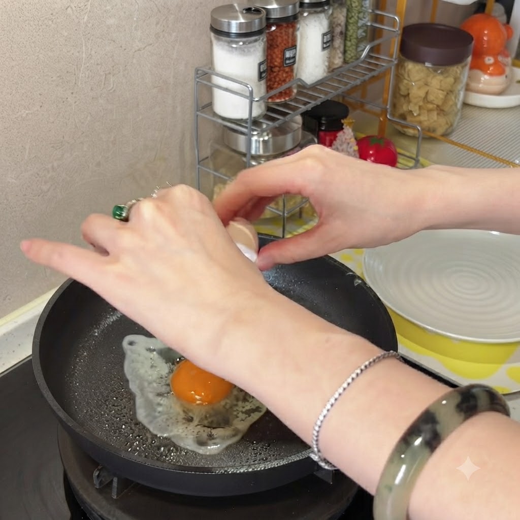 Eine Person schlägt ein Ei in eine heiße, geölte beschichtete Bratpfanne.
