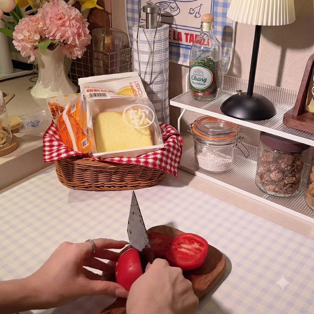 Hände schneiden mit einem Kochmesser eine leuchtend rote Tomate auf einem Holzschneidebrett in Scheiben.