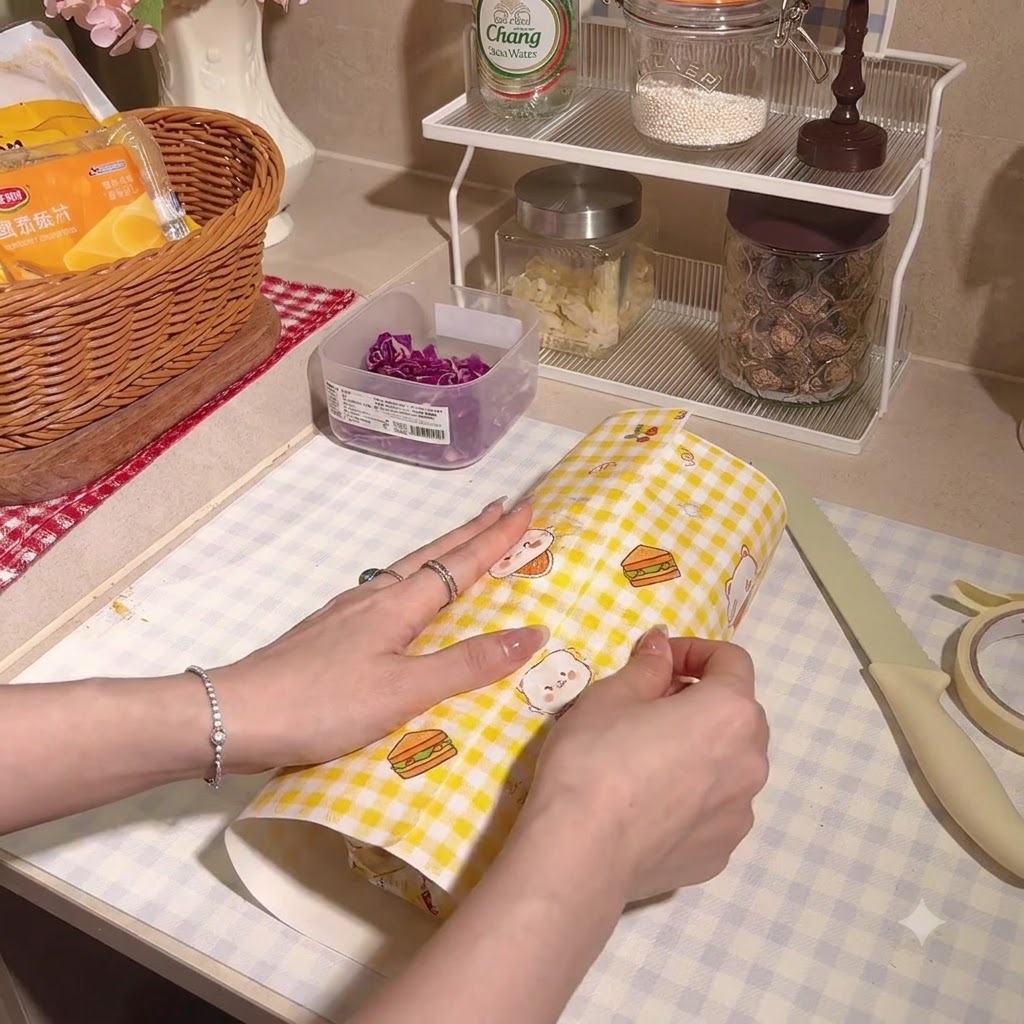 Das dicke Sandwich wird fest in kariertes Pergamentpapier eingewickelt.