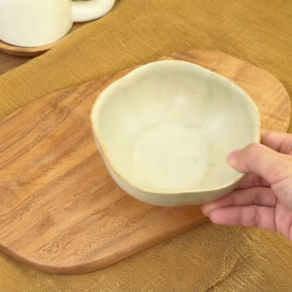 Eine kleine leere Keramikschüssel über einem Holzbrett bereit zum Mischen der Soße.