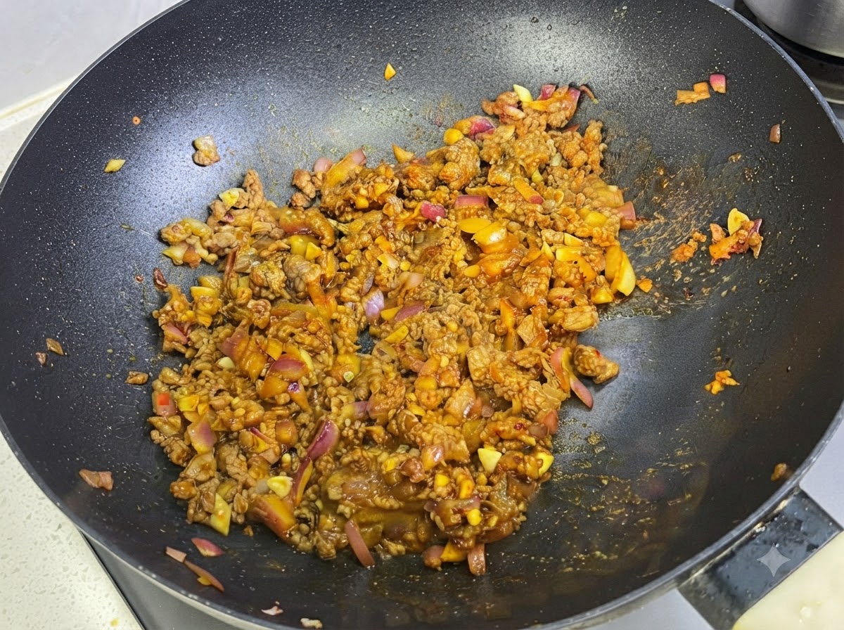 Milch wird in der Pfanne in die Curry-Fleisch-Sauce eingearbeitet.