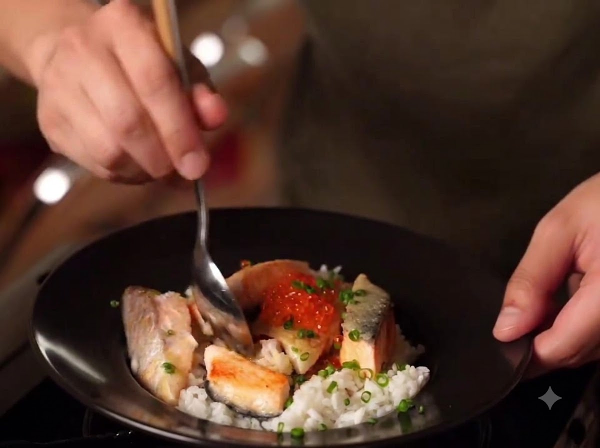 Eine Nahaufnahme einer fertigen Schale Miso-Lachs-Oyakodon mit Reis, angebratenem Lachs, Lachskaviar und Frühlingszwiebeln.
