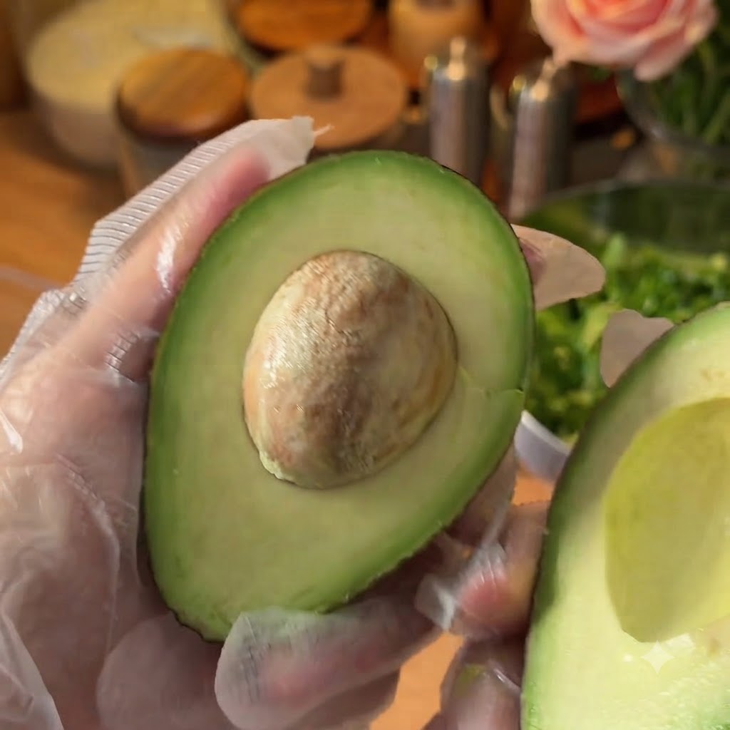 Eine halbierte frische Avocado wird auf einem Schneidebrett zubereitet.