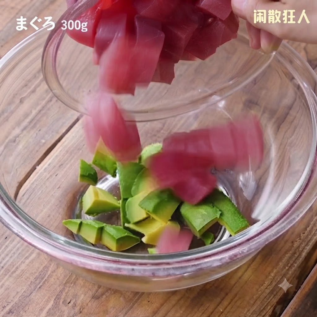 Frische Thunfischwürfel werden aus einer kleinen Schüssel in die Glasschüssel mit den Avocadowürfeln gegeben.