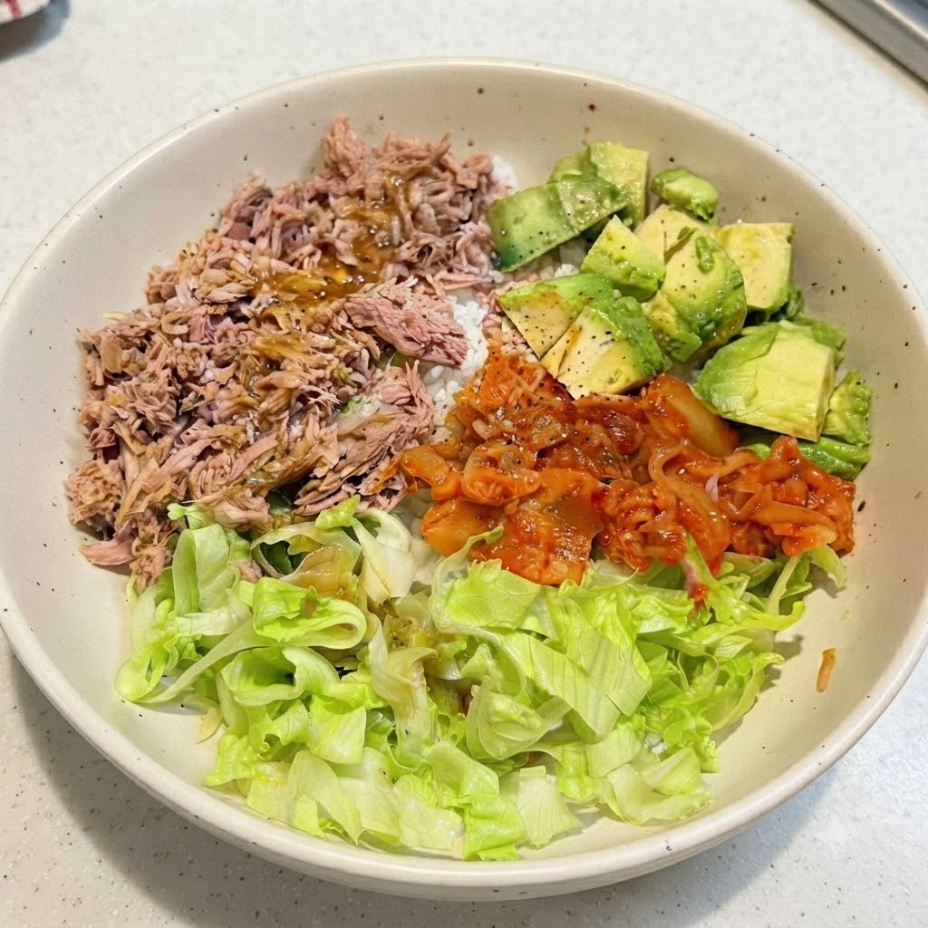Eine zubereitete Thunfisch-Avocado-Reis-Bowl mit darüber geträufeltem Dressing auf den obersten Zutaten.