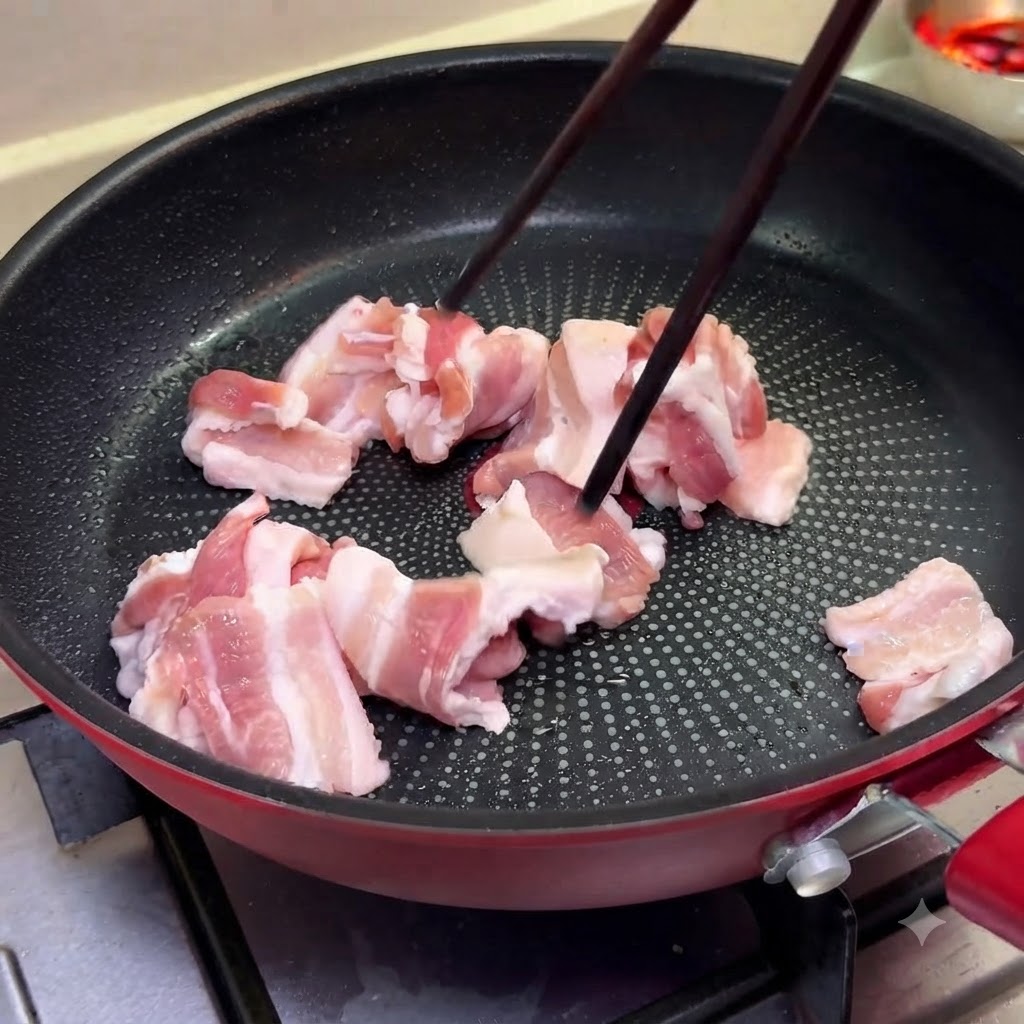 Dünne Scheiben Schweinebauch garen in einer Pfanne bei mittlerer Hitze unter Verwendung von Essstäbchen.