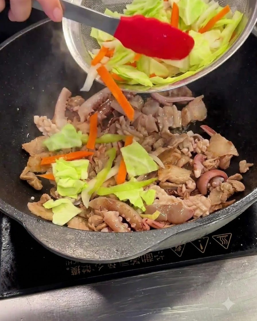 Geschnittener Kohl und Karotten werden aus einem Sieb in den Wok gegeben.