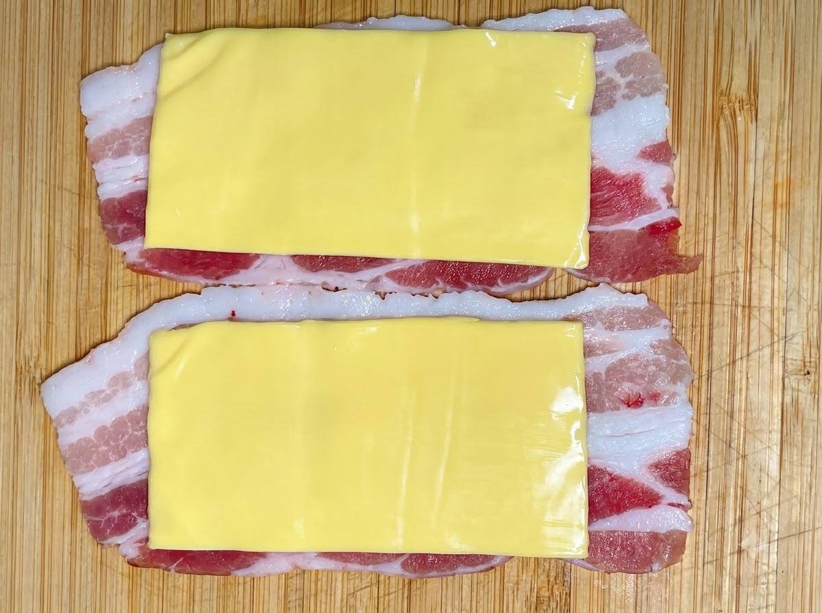 Eine Portion Garnelenpaste wird aus einem Spritzbeutel auf die Käse- und Schweineschichten gedrückt.