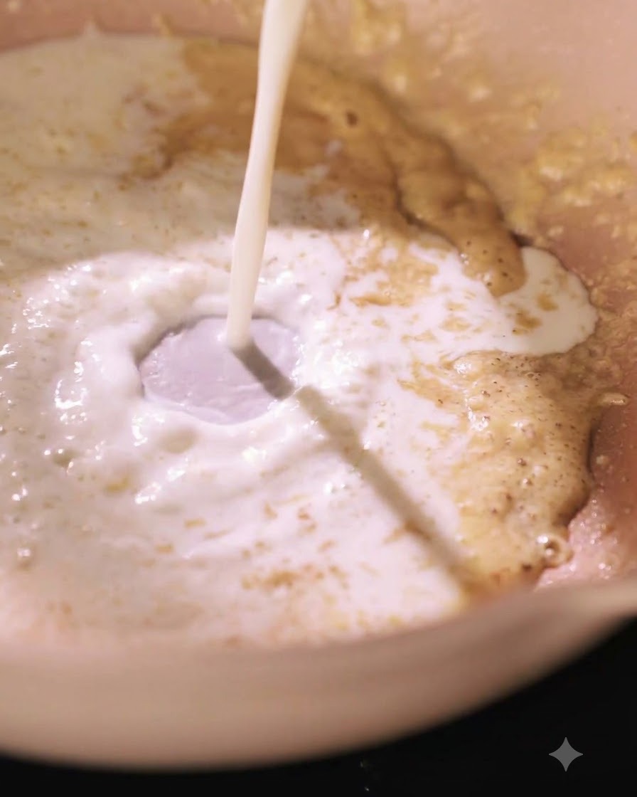 Milch wird in eine Pfanne mit einer Mehlschwitze gegossen und erzeugt einen Strudel.