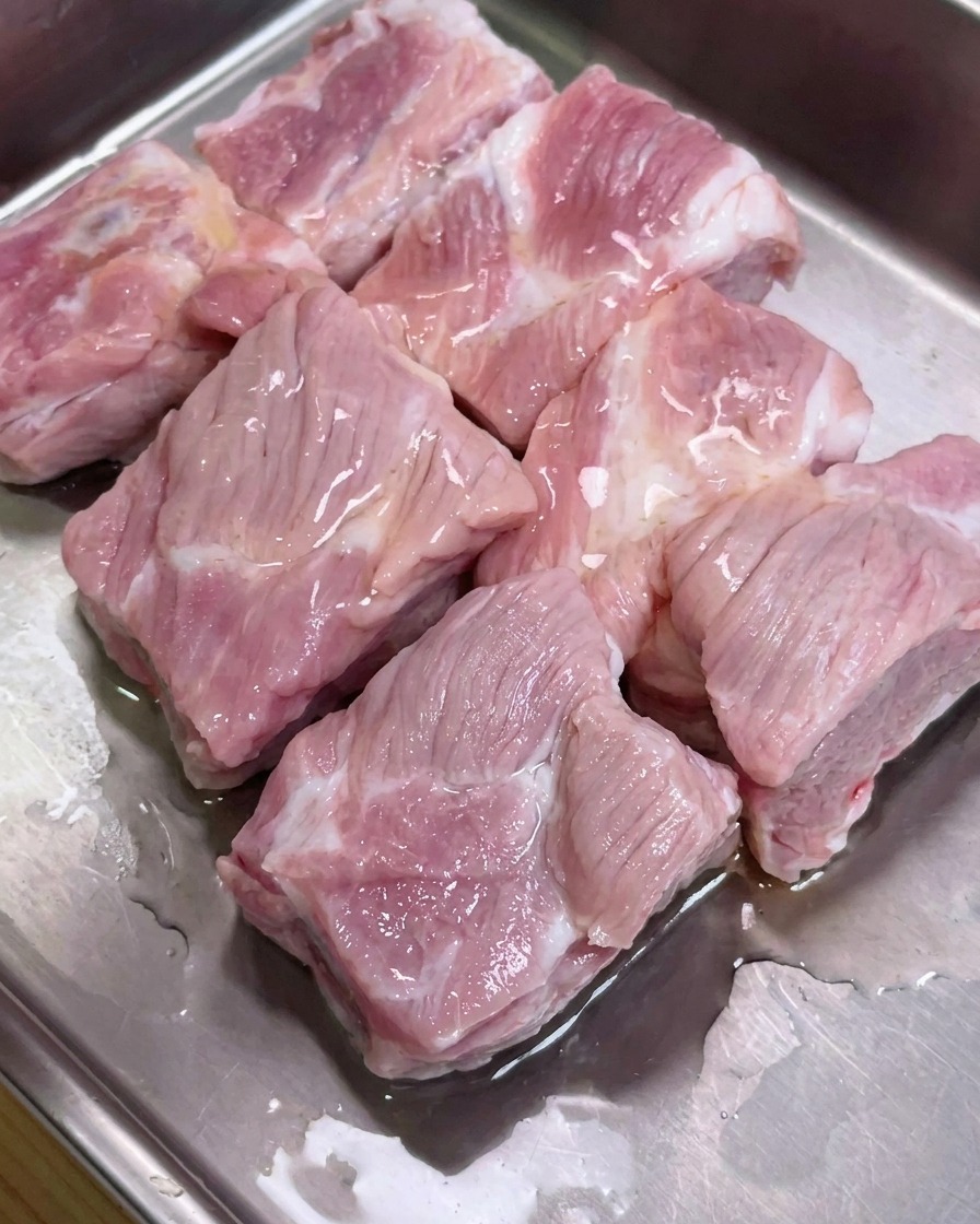 Schweinerippchen in einer Metallschale, gewürzt mit Sojasaucen, Austernsauce und Pfeffer.