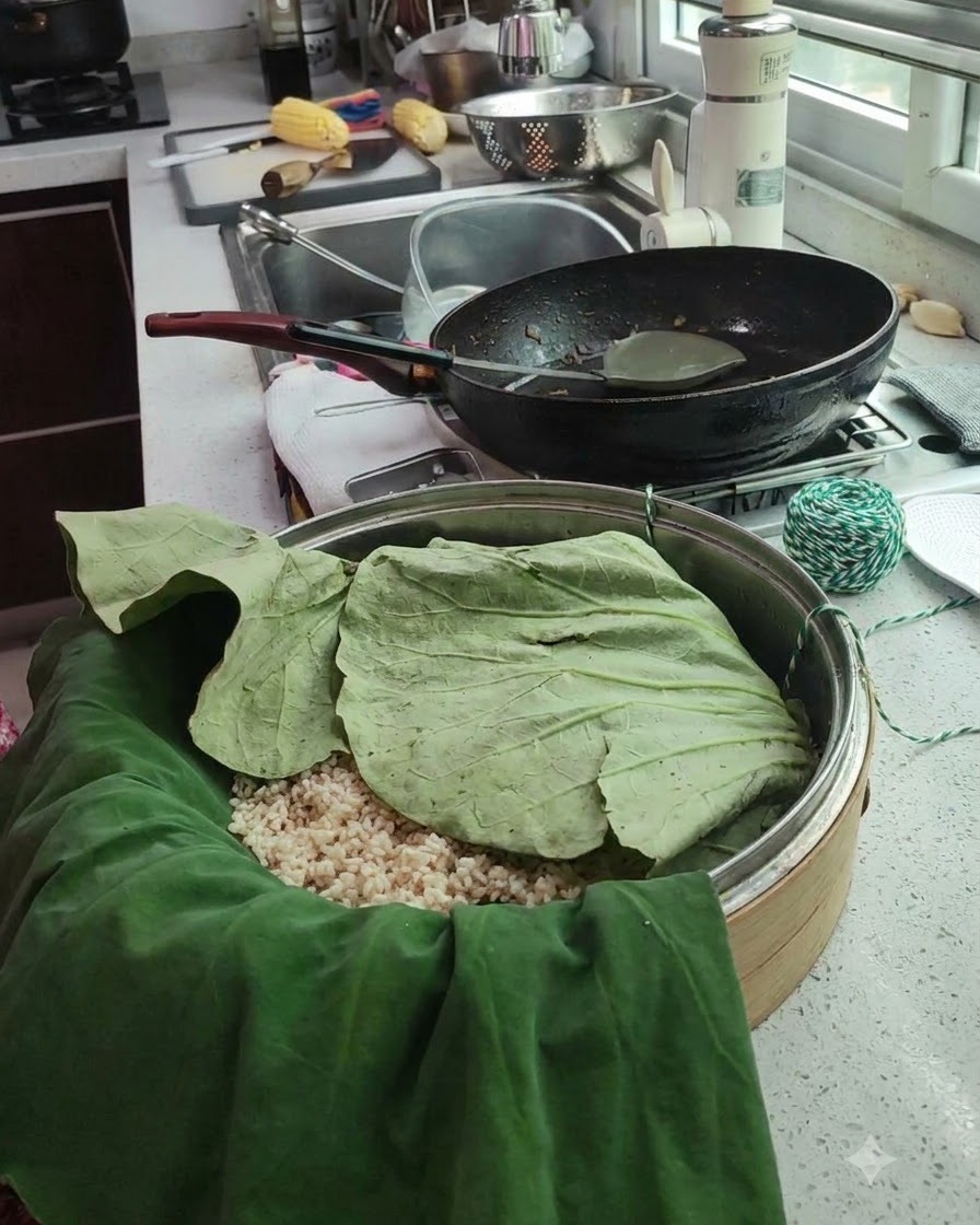 Ein eingewickeltes Lotusblattpaket liegt in einem Dämpfkorb, daneben grünes und weißes Küchengarn.