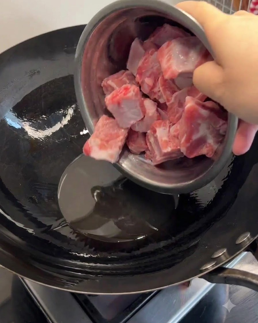 Schweinerippchen werden in geschmolzenem Schmalz in einem heißen Wok gegeben und angebraten, bis sie gebräunt sind.