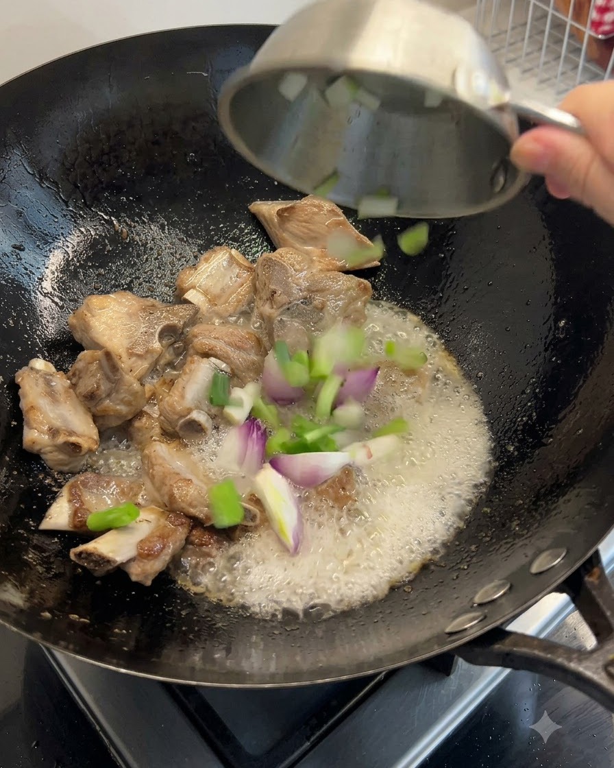 Frühlingszwiebeln, Ingwer und getrocknete Meeresfrüchte werden mit den Rippchen in den Wok gegeben.