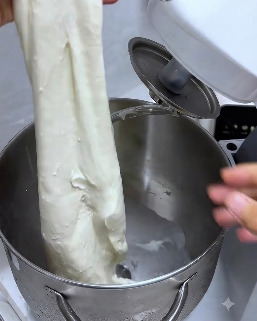 Ein Stück Teig wird gedehnt, um eine starke, elastische, handschuhähnliche Membran zu zeigen.
