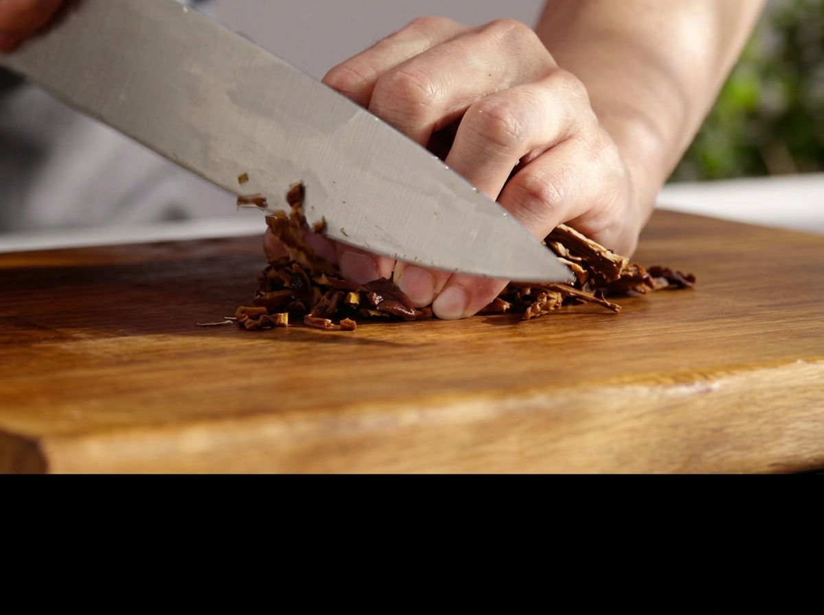 Ein Messer hackt eingeweichte Pilze fein auf einem Holzbrett.